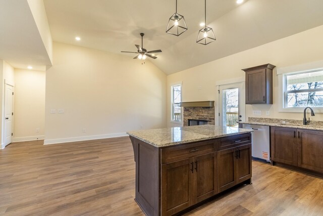 kitchen featuring lofted ceiling, a sink, open floor plan, dishwasher, and light wood finished floors