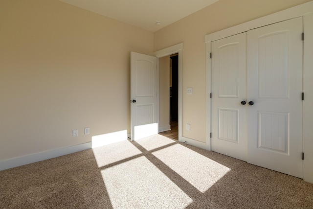 unfurnished bedroom featuring a closet, baseboards, and carpet flooring