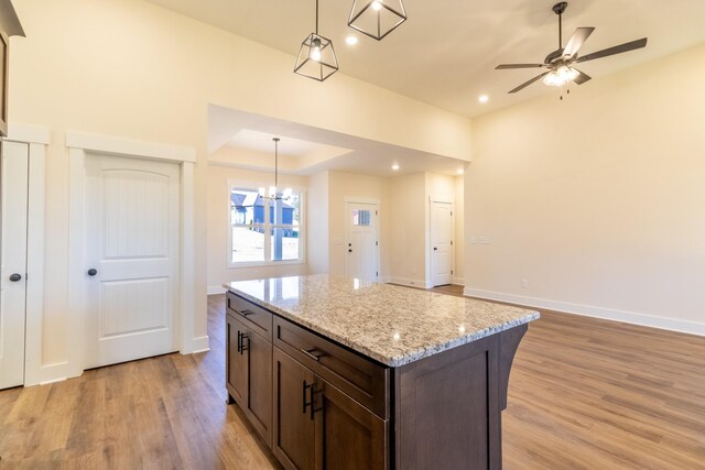 kitchen with light wood-style floors, baseboards, dark brown cabinets, and decorative light fixtures