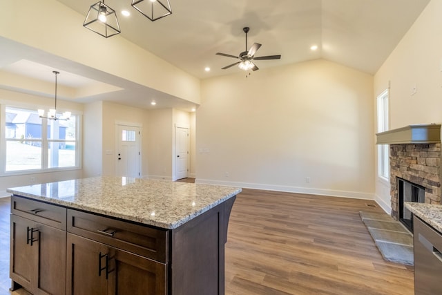 kitchen with light wood finished floors, a stone fireplace, open floor plan, and baseboards