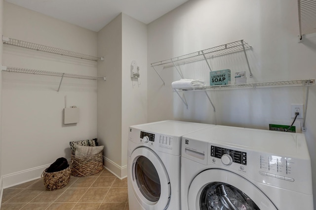 laundry room featuring laundry area, washing machine and dryer, light tile patterned floors, and baseboards