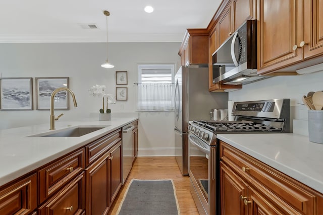 kitchen with a sink, visible vents, appliances with stainless steel finishes, and crown molding