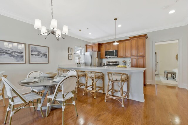 dining room with recessed lighting, light wood-type flooring, and crown molding