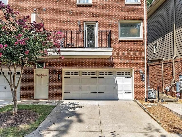 view of front facade with driveway, brick siding, an attached garage, and a balcony