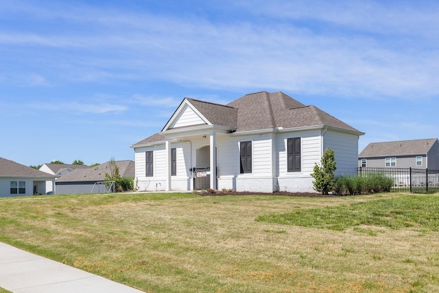 view of front of property featuring a shingled roof, brick siding, fence, and a front lawn