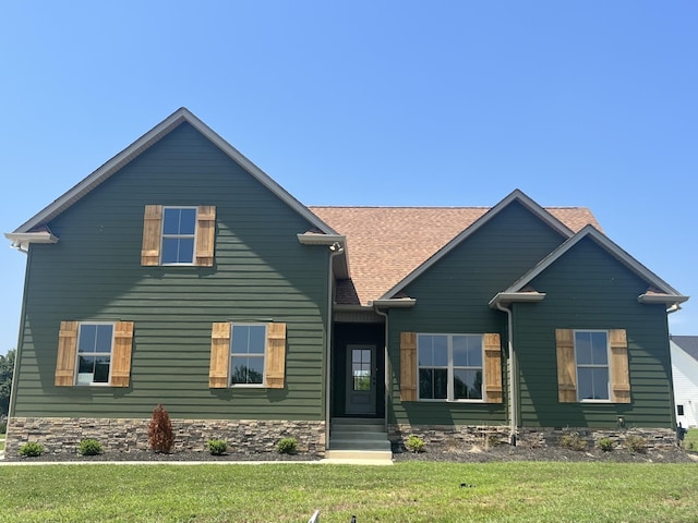 view of front of property with entry steps, a shingled roof, and a front yard