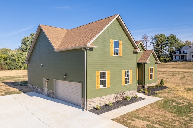 view of property exterior featuring a garage, roof with shingles, and driveway