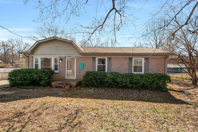 ranch-style home featuring a shingled roof, brick siding, fence, and a gambrel roof