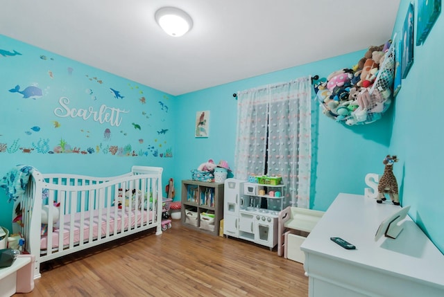 bedroom featuring a crib and wood finished floors