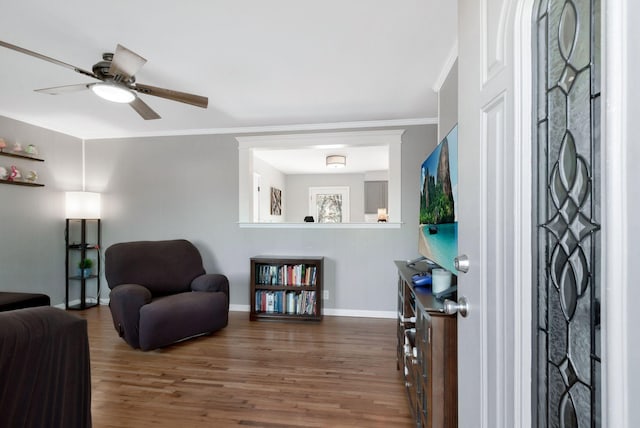 living area with crown molding, baseboards, ceiling fan, and wood finished floors