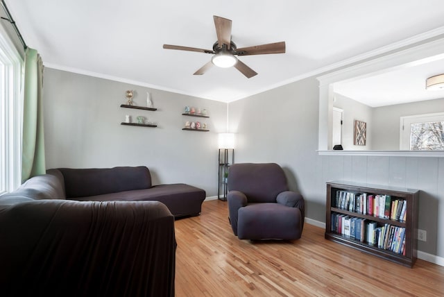 living area featuring ceiling fan, ornamental molding, wood finished floors, and baseboards