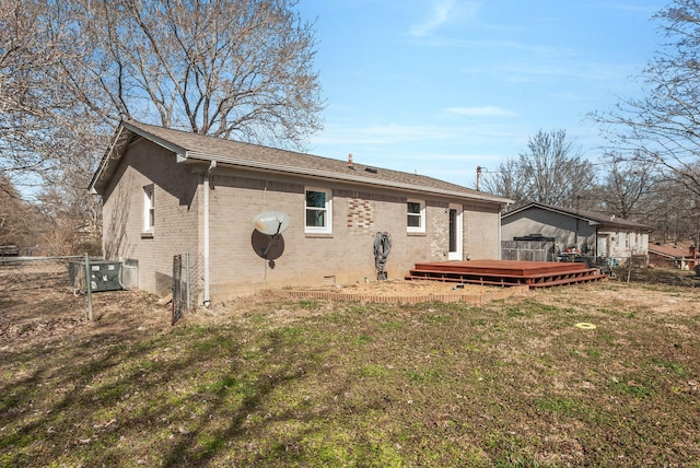 back of house with brick siding, a lawn, crawl space, fence, and a wooden deck