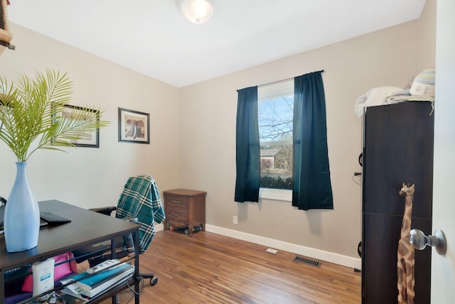 office area with visible vents, baseboards, and wood finished floors