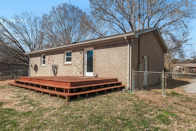 rear view of property with brick siding, fence, a lawn, and a wooden deck