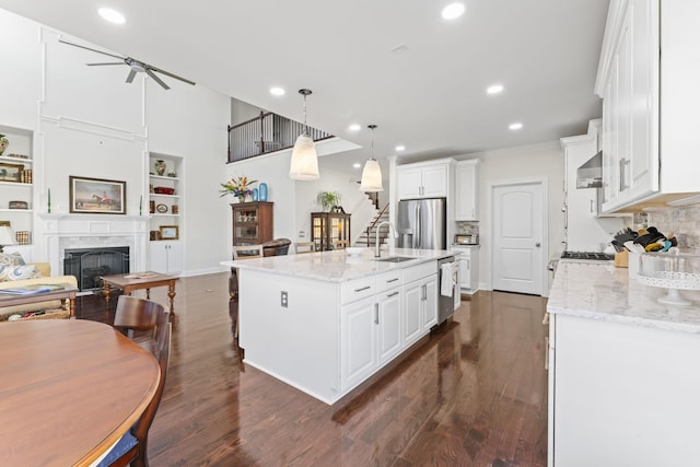 kitchen with a premium fireplace, dark wood-style flooring, stainless steel appliances, white cabinetry, and a sink