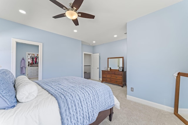 bedroom with light carpet, baseboards, a walk in closet, and recessed lighting