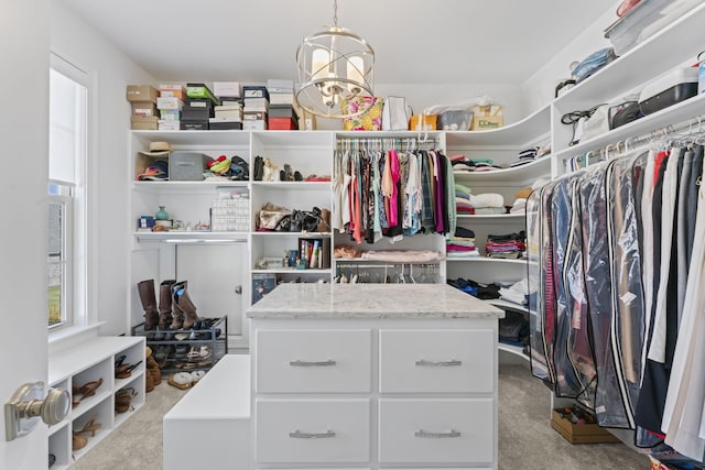 walk in closet with a chandelier and light colored carpet