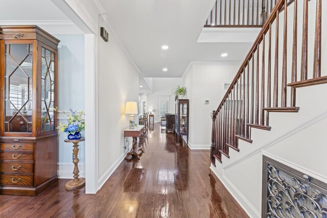 foyer with stairs, baseboards, dark wood finished floors, and crown molding