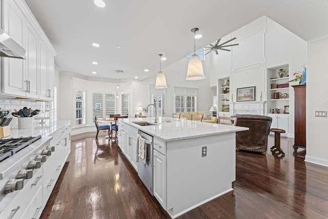 kitchen featuring dark wood-type flooring, stainless steel appliances, wall chimney range hood, white cabinetry, and a sink