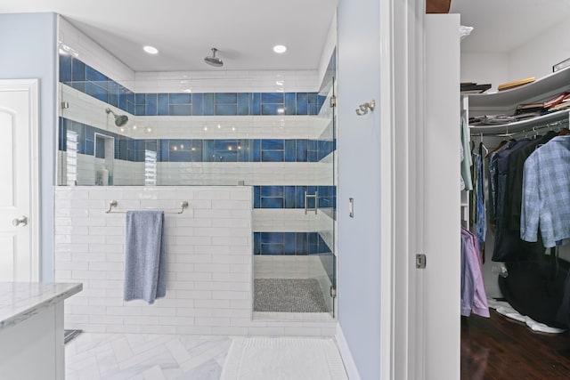 bathroom featuring a stall shower, a spacious closet, and recessed lighting