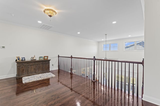 hallway featuring visible vents, crown molding, baseboards, and wood finished floors