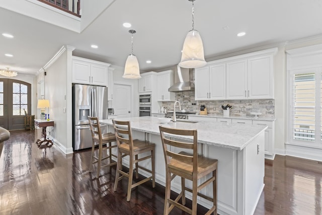 kitchen with stainless steel appliances, dark wood-style flooring, wall chimney range hood, french doors, and backsplash