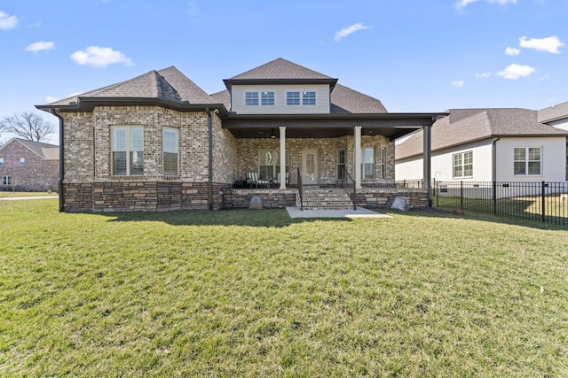 view of front facade with brick siding, roof with shingles, a front yard, and fence