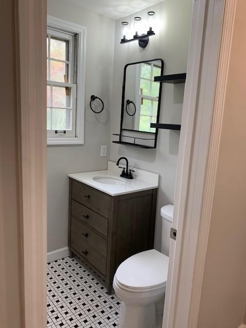 half bathroom with toilet, baseboards, and vanity