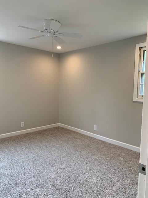 carpeted spare room with baseboards and a ceiling fan