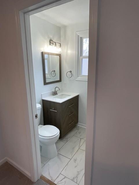 bathroom with toilet, marble finish floor, baseboards, and vanity