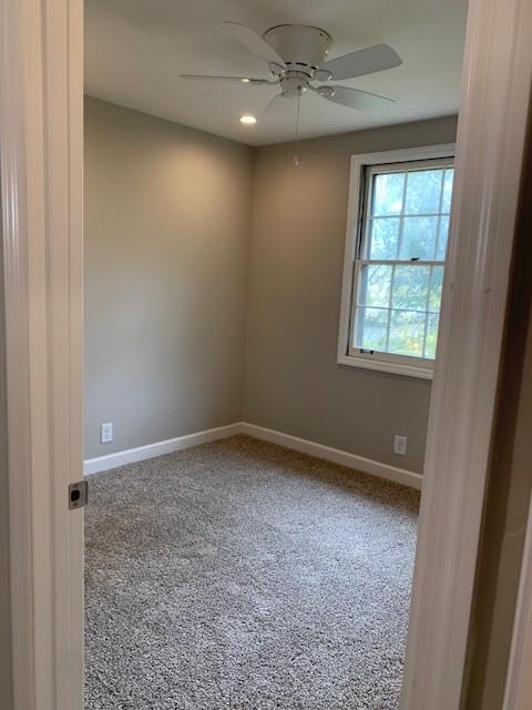 carpeted spare room with ceiling fan and baseboards