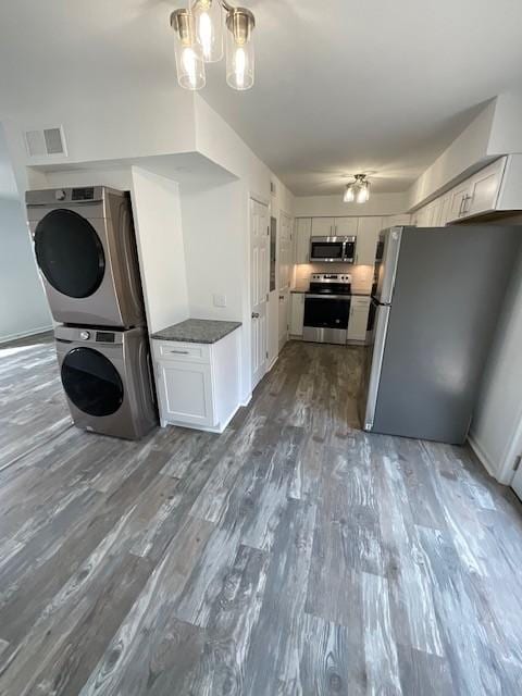 kitchen with stacked washer and clothes dryer, dark wood-style flooring, visible vents, appliances with stainless steel finishes, and white cabinets