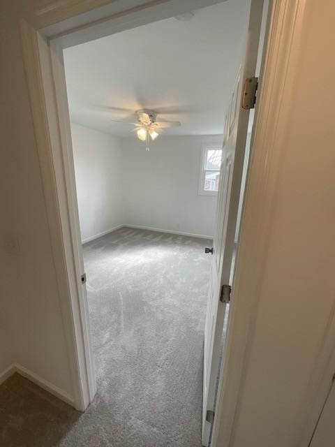 carpeted empty room with ceiling fan and baseboards