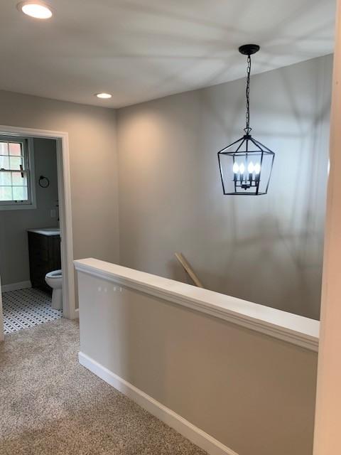 hall with recessed lighting, light colored carpet, and baseboards