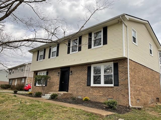 view of front of home with a front yard, crawl space, and brick siding