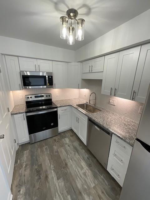 kitchen with stainless steel appliances, tasteful backsplash, dark wood-style flooring, and a sink