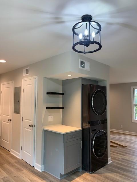 laundry area featuring light wood-style flooring, visible vents, and stacked washer / dryer