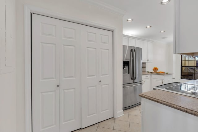 kitchen with ornamental molding, white cabinetry, stainless steel refrigerator with ice dispenser, and light tile patterned flooring