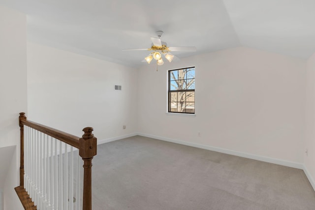 carpeted spare room with baseboards, visible vents, vaulted ceiling, and a ceiling fan