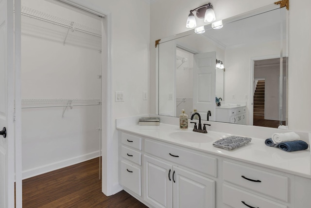 full bath featuring a spacious closet, baseboards, wood finished floors, and vanity