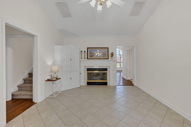 unfurnished living room featuring a ceiling fan, a glass covered fireplace, visible vents, and light tile patterned floors