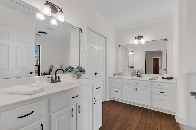 bathroom featuring ornamental molding, two vanities, a sink, and wood finished floors