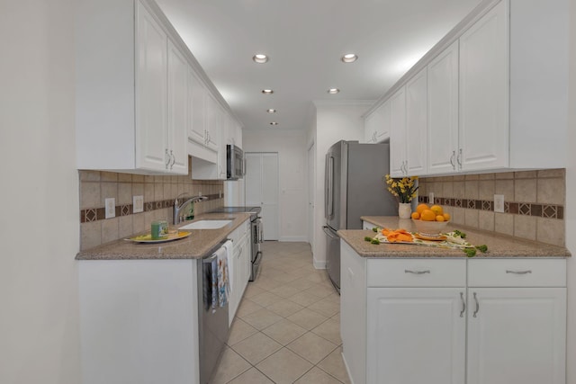 kitchen with crown molding, light tile patterned floors, appliances with stainless steel finishes, white cabinetry, and a sink