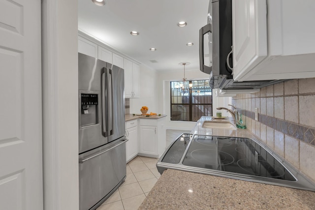 kitchen with light tile patterned floors, decorative backsplash, appliances with stainless steel finishes, white cabinetry, and a sink