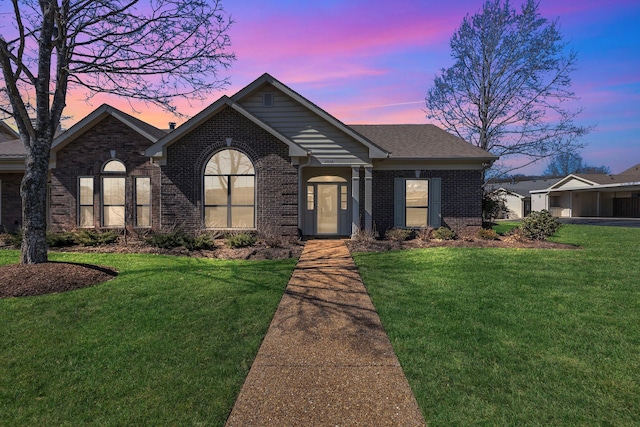 single story home with brick siding, a front yard, and a shingled roof