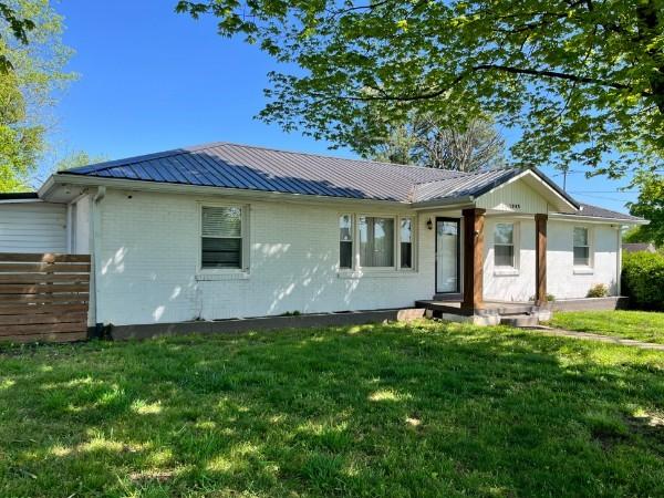 single story home with brick siding, metal roof, and a front lawn