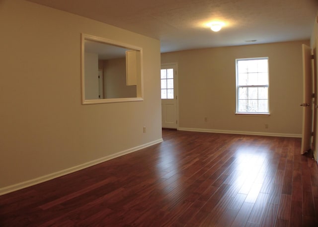 empty room featuring dark wood-type flooring and baseboards