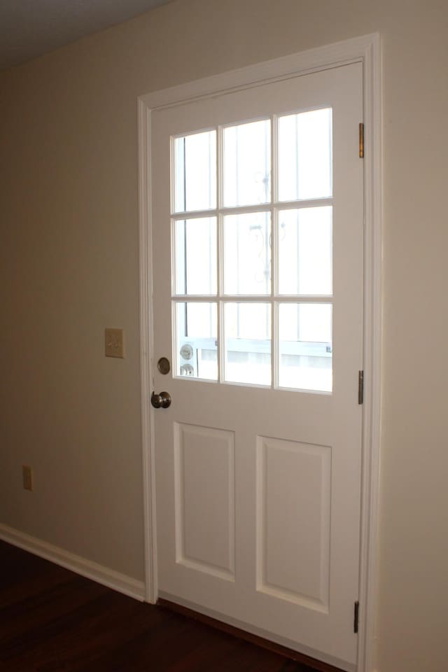 doorway with dark wood-style flooring and baseboards