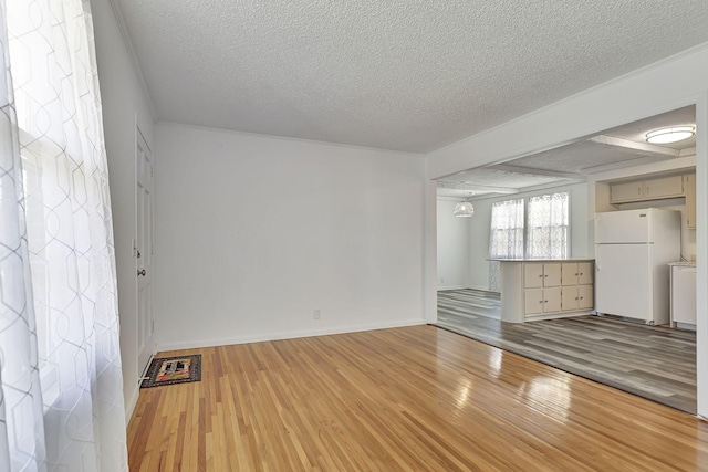 unfurnished living room with a textured ceiling, light wood-style flooring, and baseboards