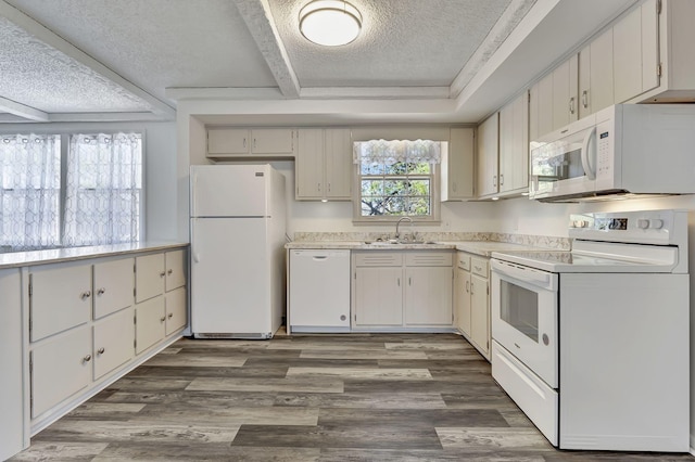 kitchen with a textured ceiling, white appliances, wood finished floors, a sink, and light countertops